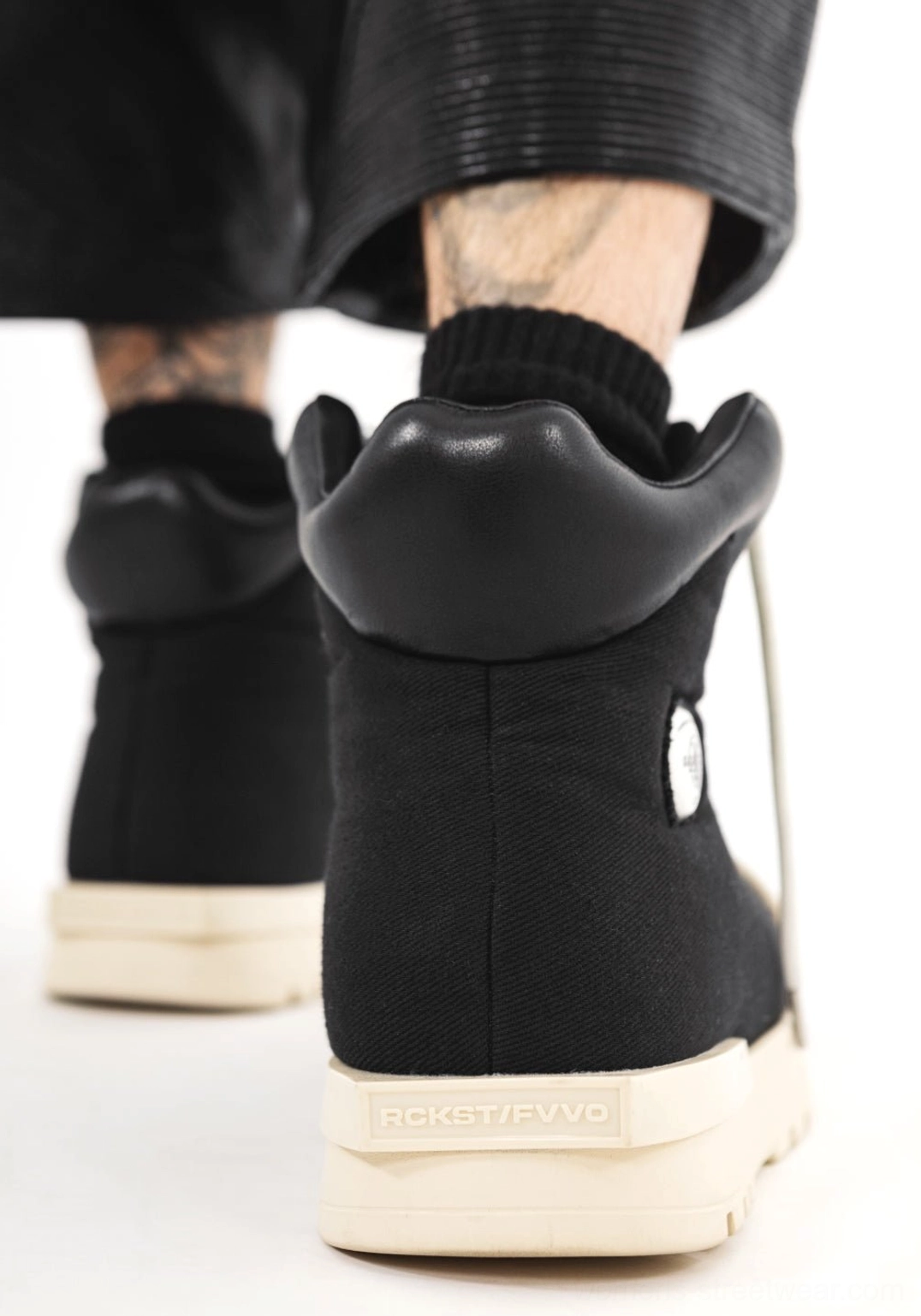 Rear view of black high-top platform boots showing padded ankle collars, contrasting off-white soles, structured heel, and chunky streetwear silhouette