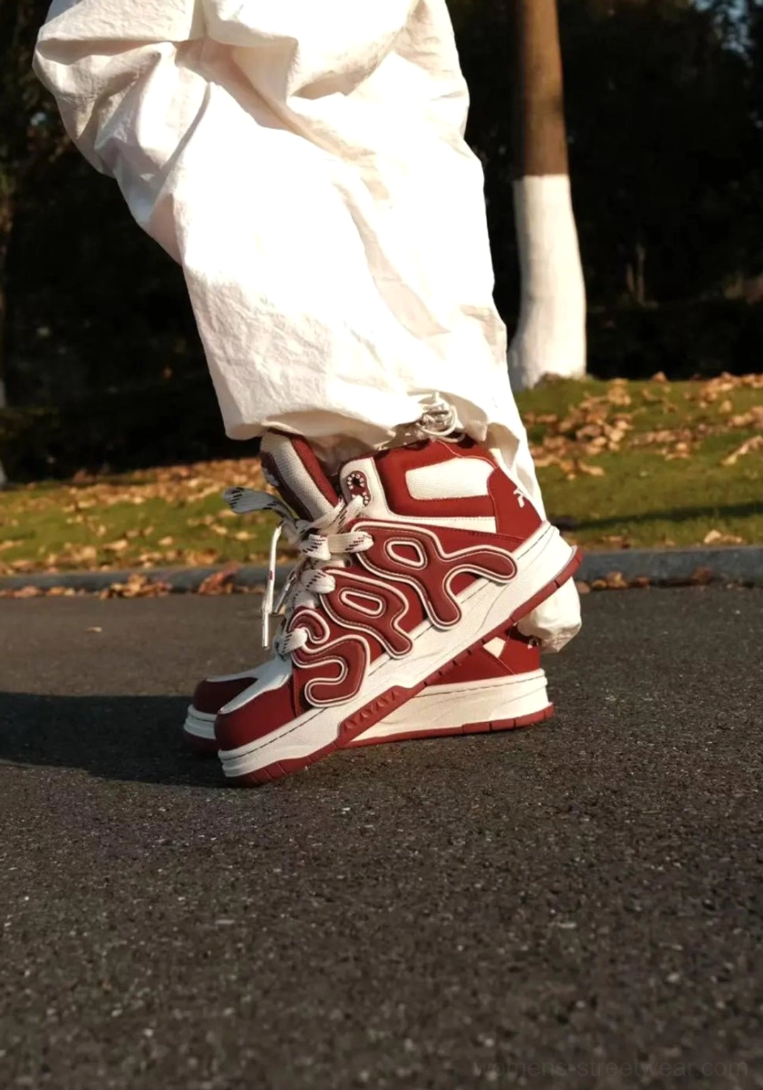 Side rear view of black high-top skate sneakers worn with cargo pants, showing oversized letter patterns and thick platform sole