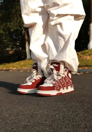 Black and off-white high-top skate sneakers worn with off-white cargo pants on an outdoor asphalt street covered with autumn leaves