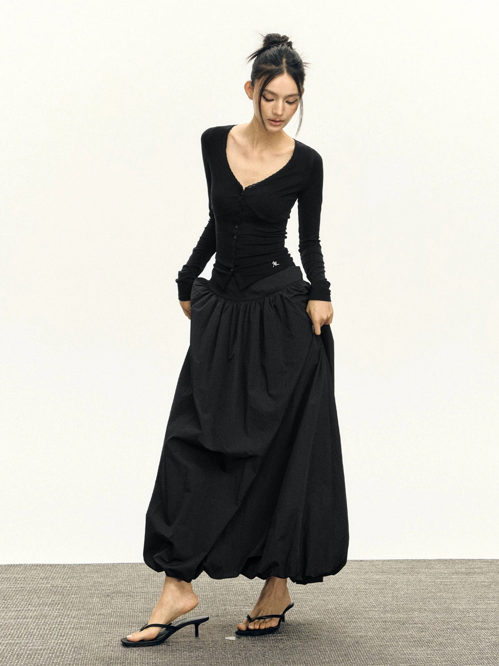 Black high waisted balloon maxi skirt styled with fitted black long sleeve top in three-quarter front view