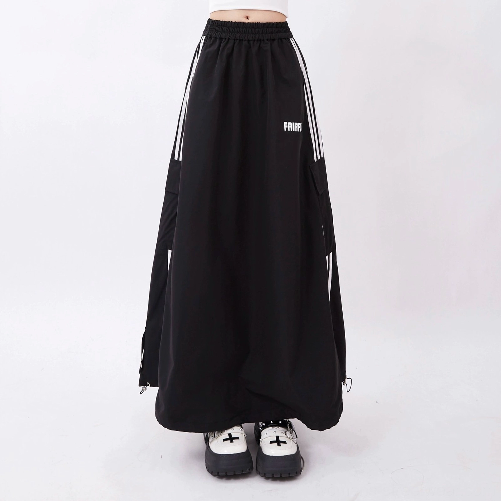 Black high-waisted cargo maxi skirt flat lay with white racing stripes, oversized utility pockets, and platform sneaker styling reference