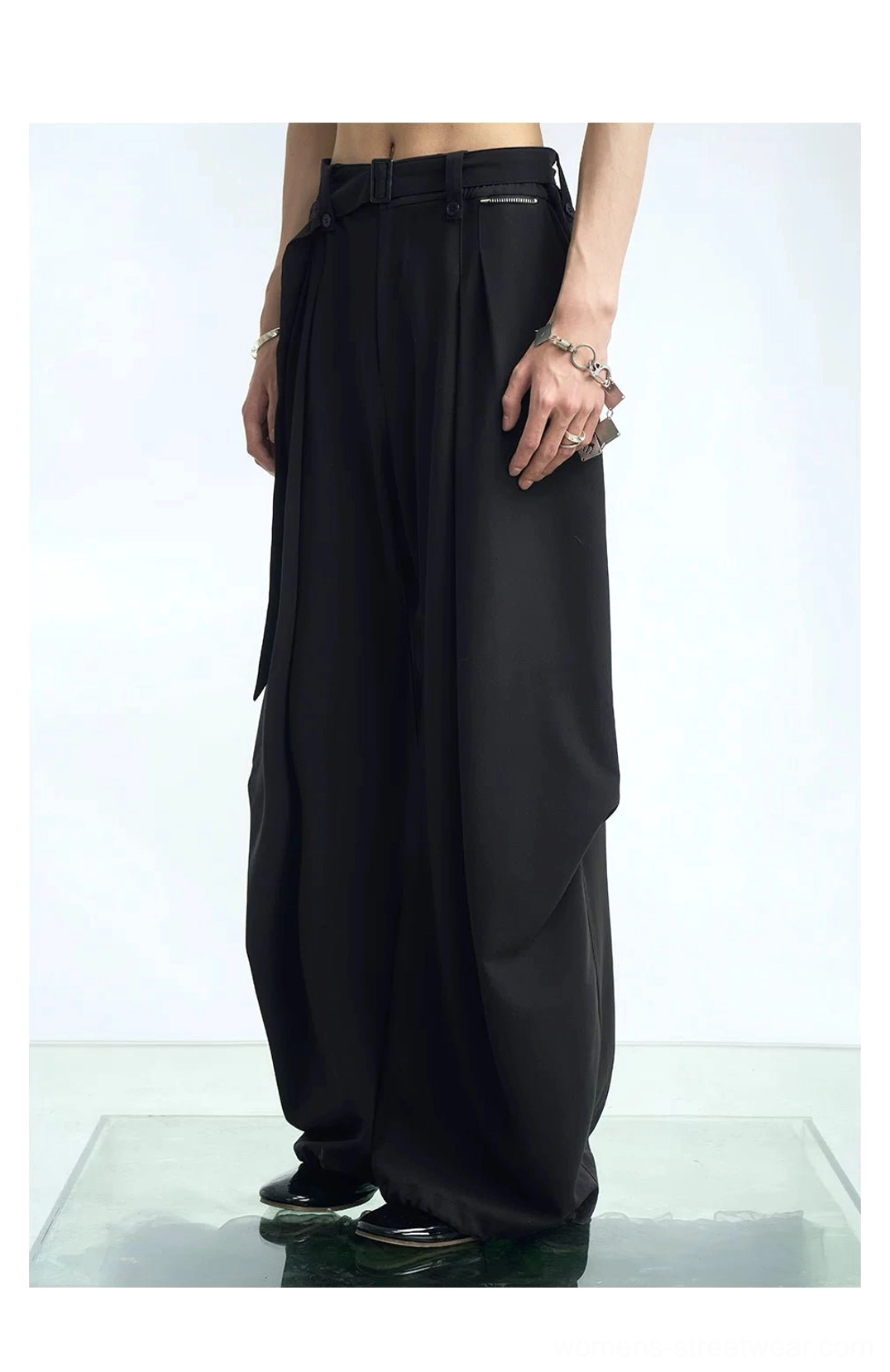 Black high-waisted pleated balloon wide-leg streetwear pants shown in a front three-quarter studio view with oversized draped legs and contemporary urban styling