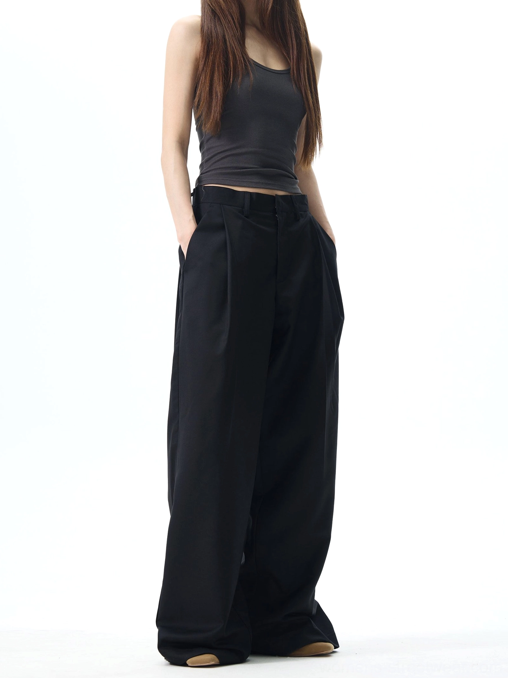 Black high-waisted pleated wide-leg streetwear dress pants shown from the front on a female model with floor-length trousers and side pockets