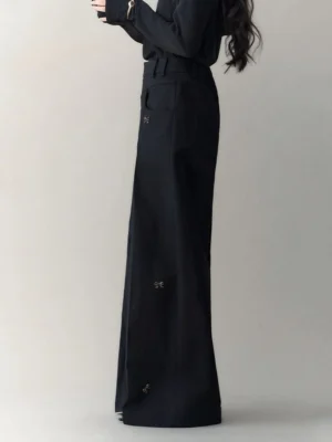 Back view of high-waisted black wide-leg streetwear trousers with belt loops and scattered bow embellishments