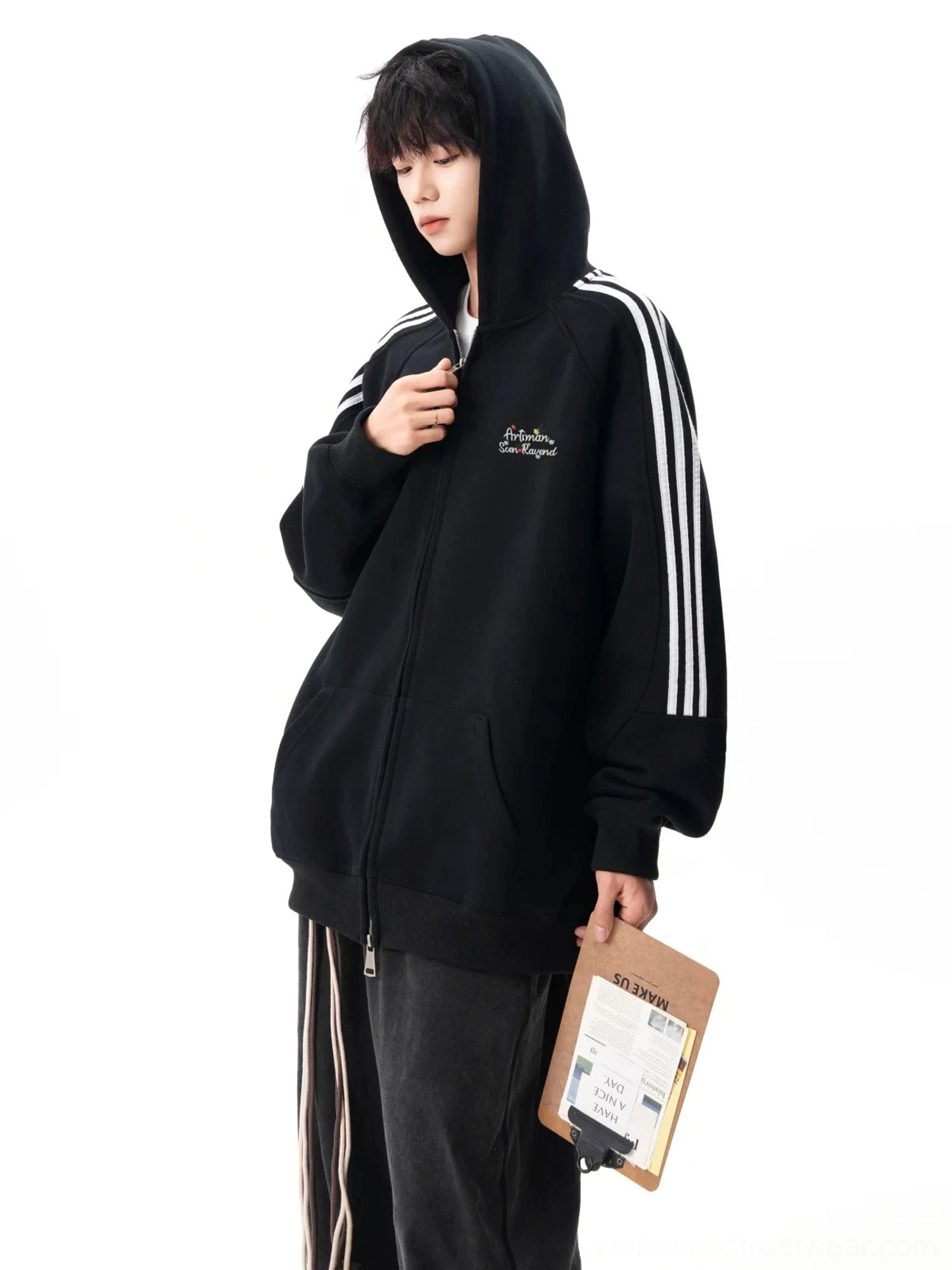Black oversized zip hoodie worn with the hood up, showing embroidered chest lettering, triple sleeve stripes, and relaxed Korean fashion styling