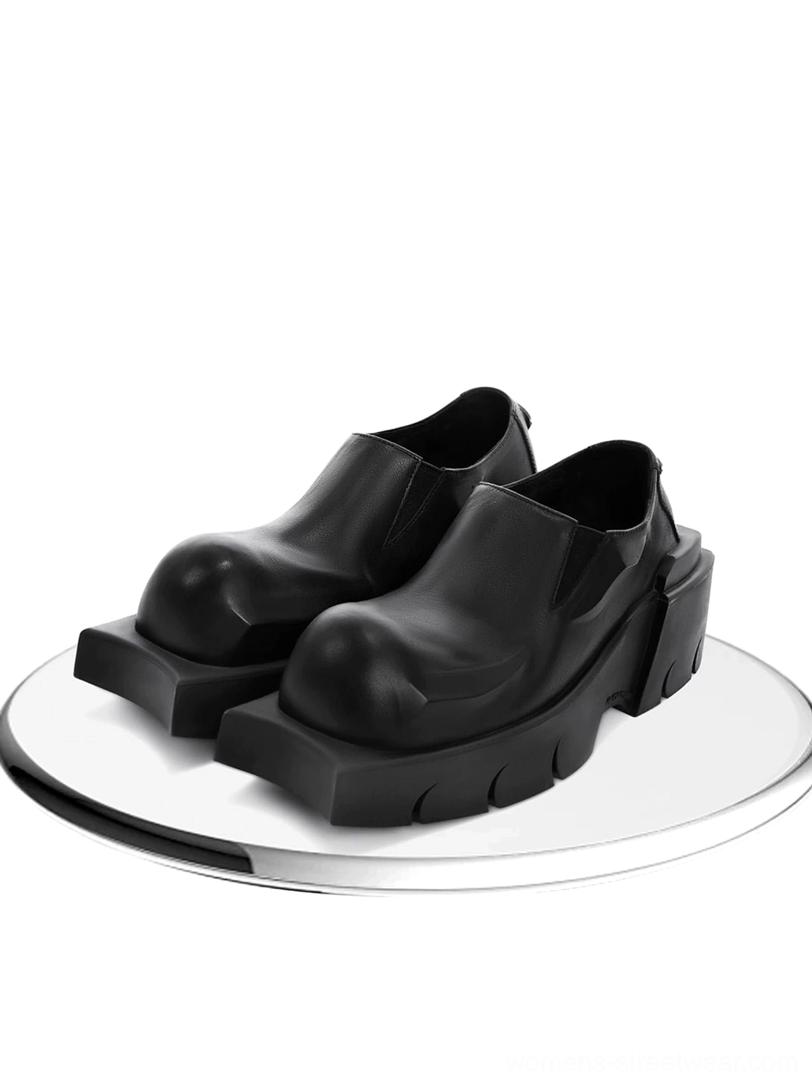 Black horn-detail leather platform derby shoes displayed on a round mirror stand with smooth polished black leather uppers