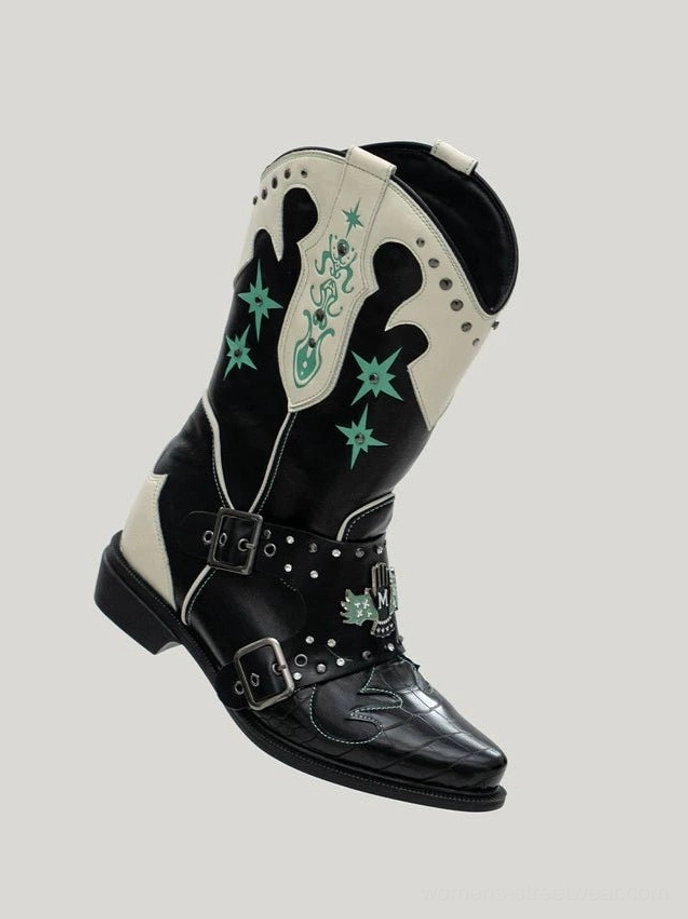 Side profile of black and ivory women's cowboy harness boots with green western embroidery, dual studded buckle straps, and a low block heel