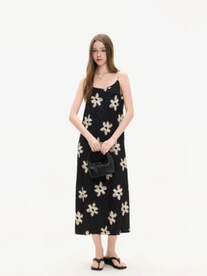 Front full body view of a black floral applique slip midi dress with ivory daisy details and slim shoulder straps in a clean studio setting