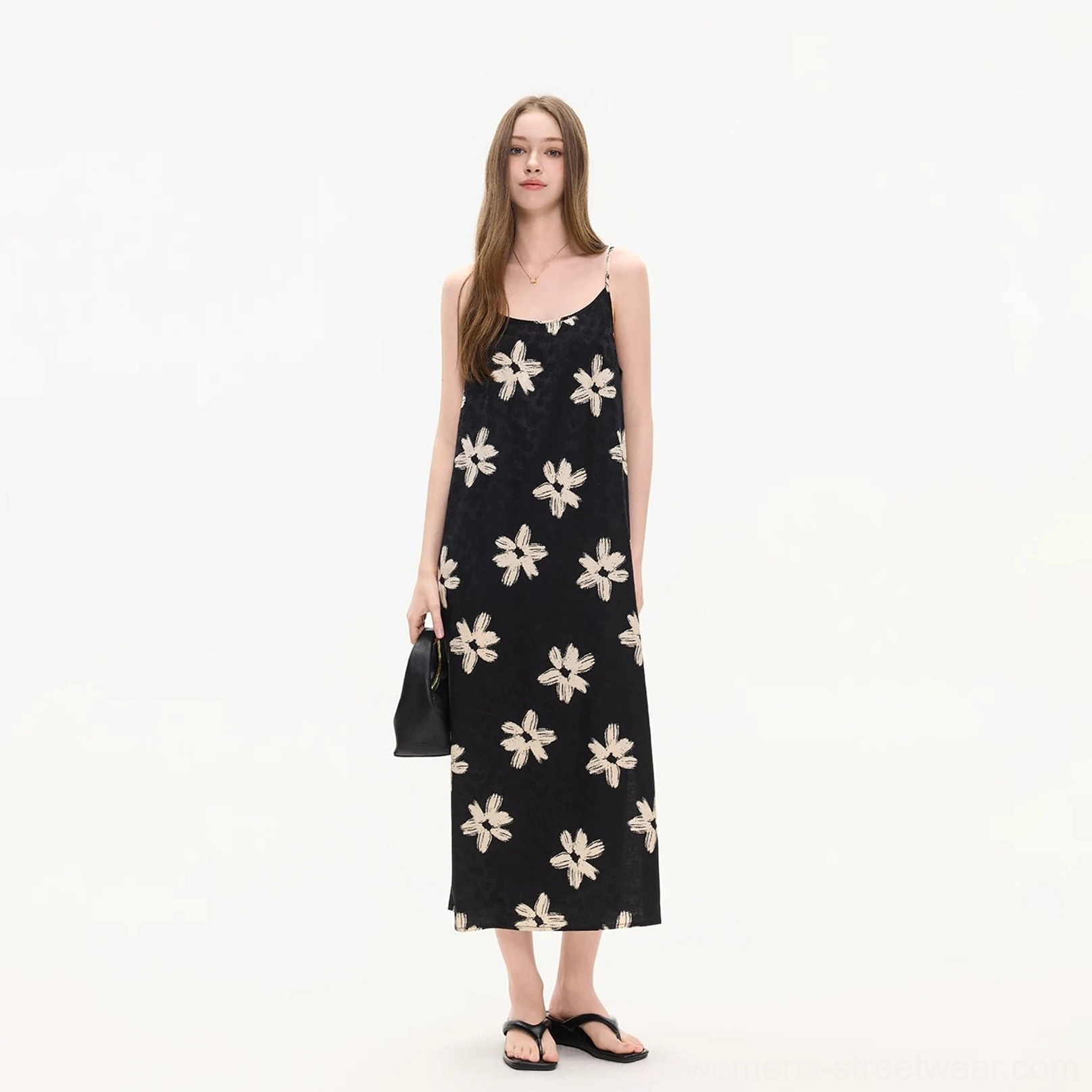 Three quarter side view of a black ivory floral applique slip midi dress with spaghetti straps and ankle grazing length