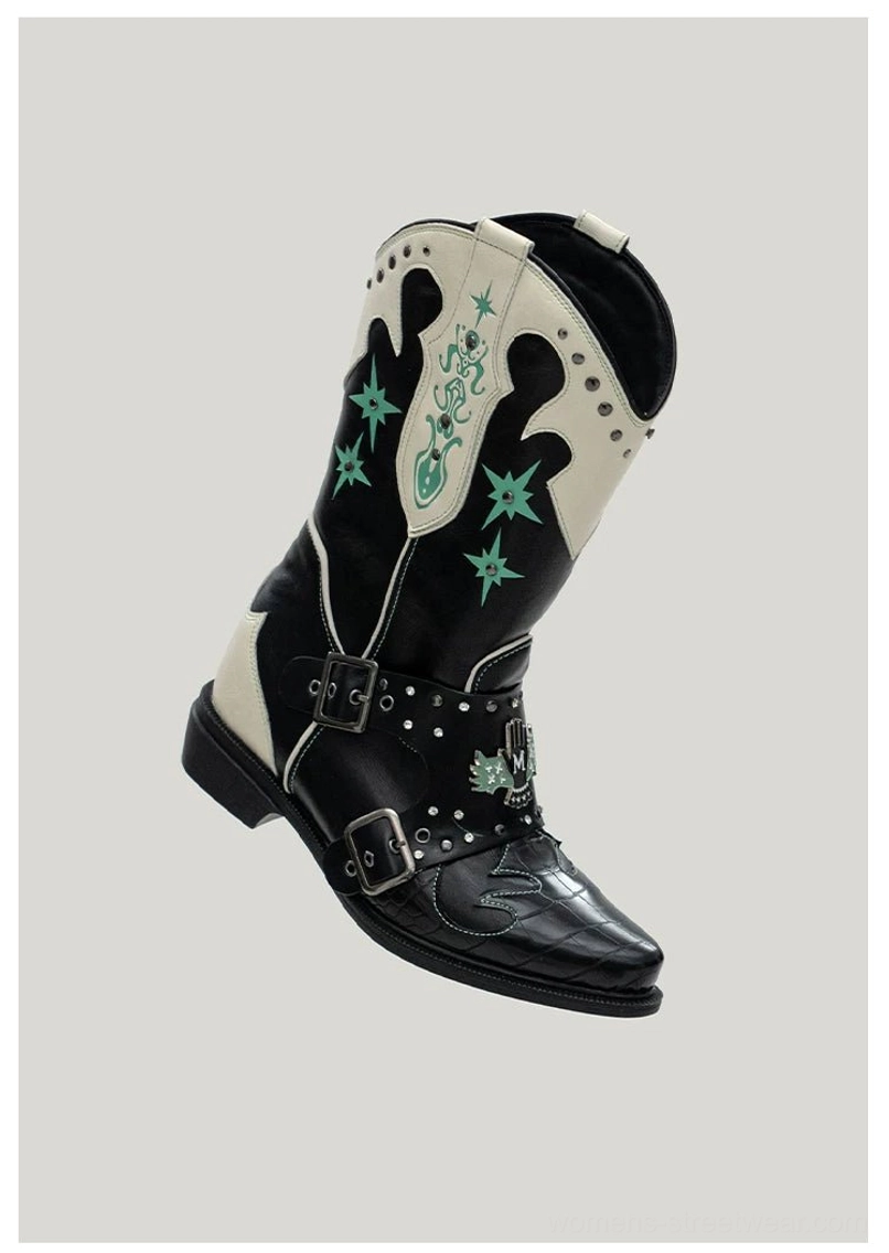 Angled side view of black and ivory western harness boots with green star details, studded double buckle straps, pointed toes, and low heels