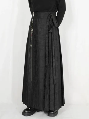 Black jacquard pleated maxi skirt with side tie sash and tassel chain styled with black turtleneck and platform loafers