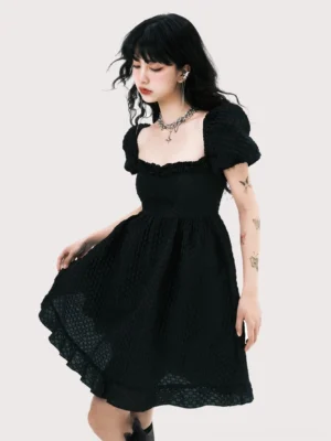 Three-quarter view of a black jacquard mini dress featuring short puff sleeves, fitted bust, ruffled hem, and flowing A-line skirt