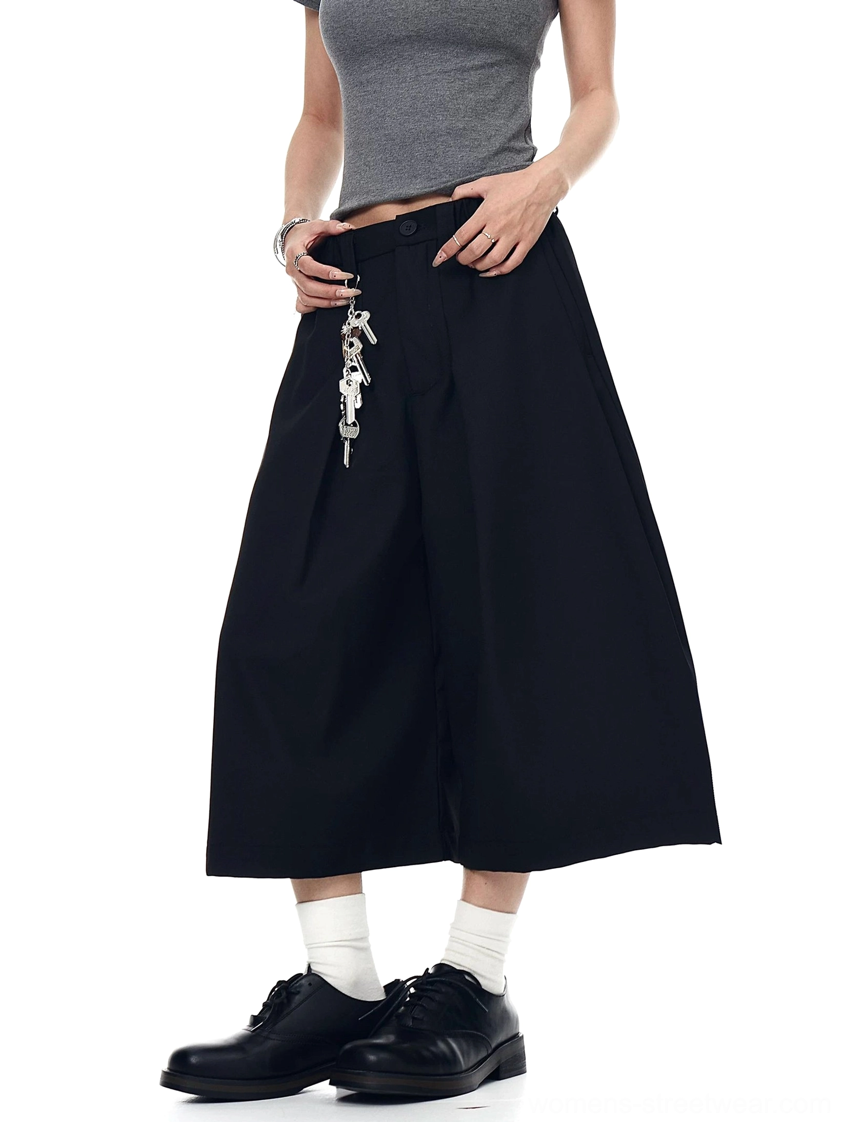 Black keyring pleated wide-leg culotte trousers shown from a front and back three-quarter angle with a cropped streetwear silhouette