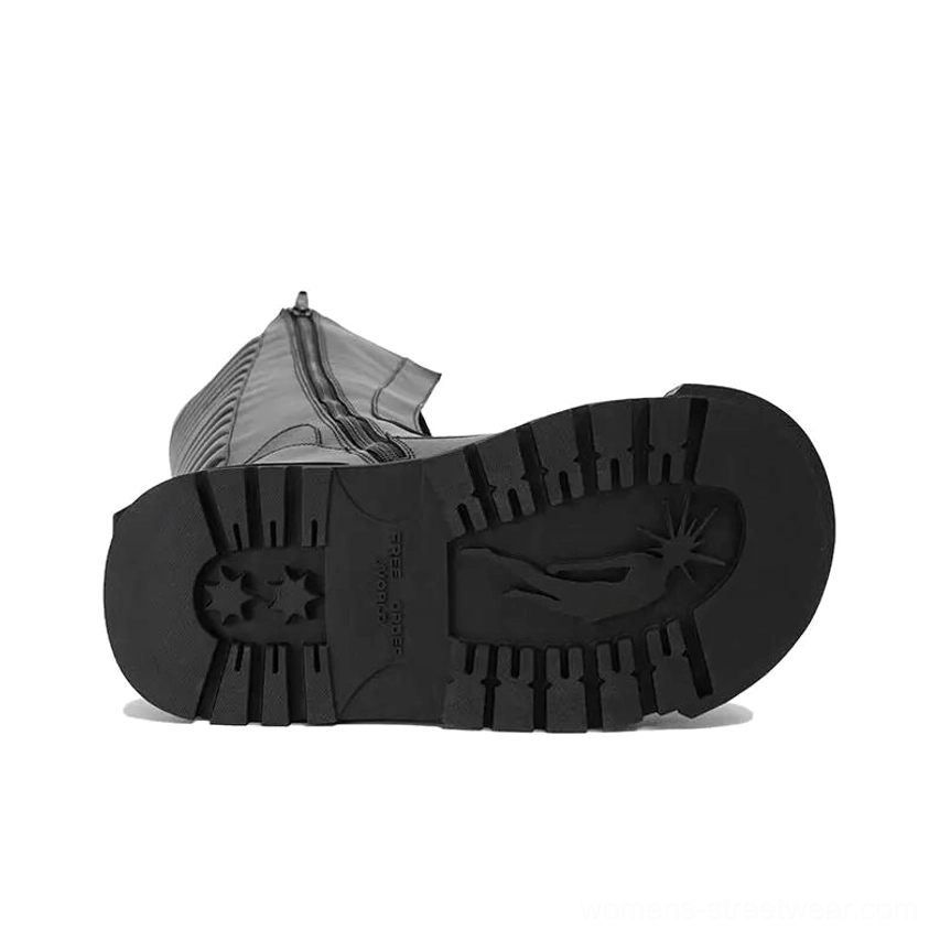 Close top-down view of the deep tread outsole on black knee-high platform combat boots with an aggressive star-inspired pattern