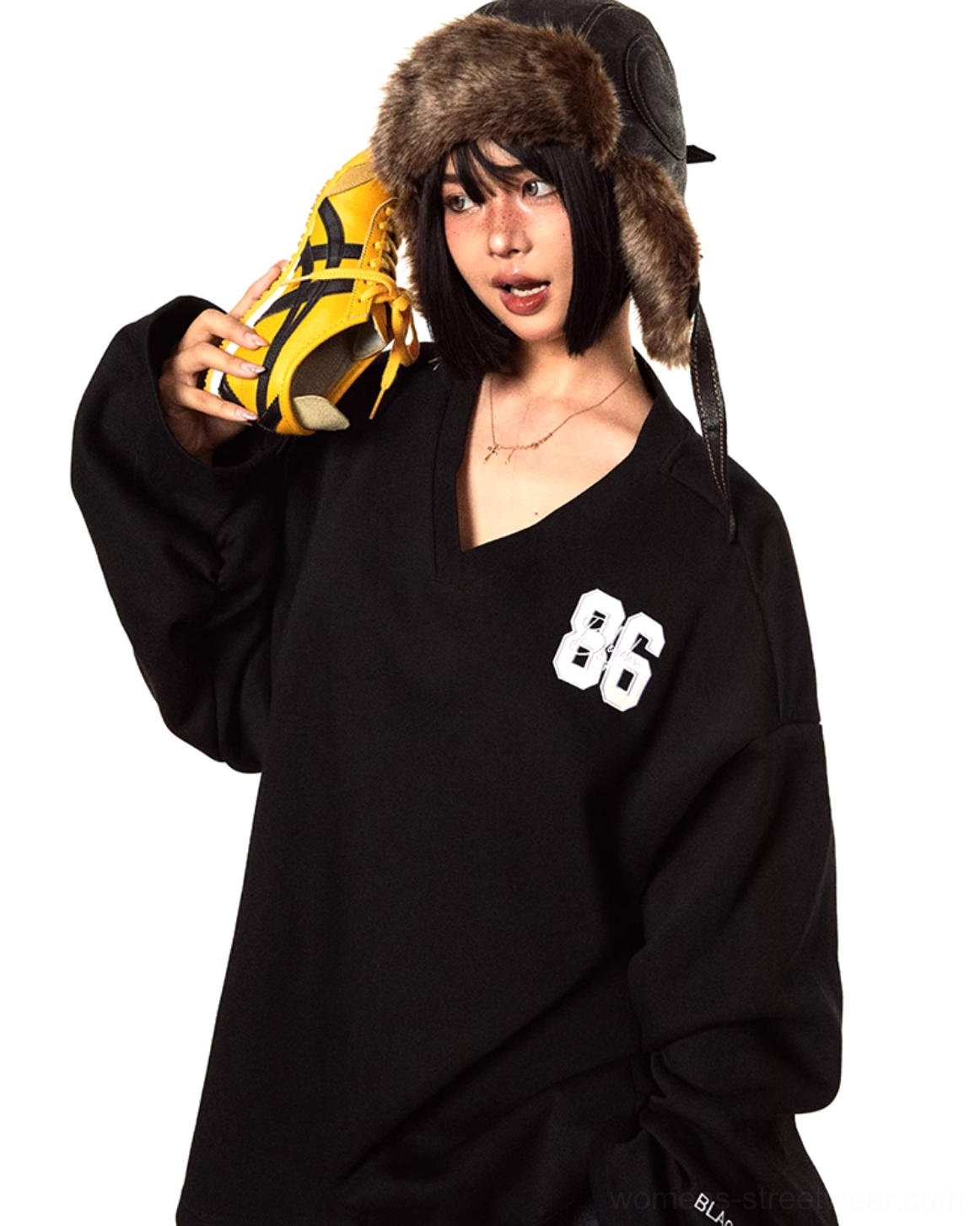 Close-up front view of a black oversized knit V-neck sweater featuring large 86 embroidery on the left chest and extra-long drop shoulder sleeves