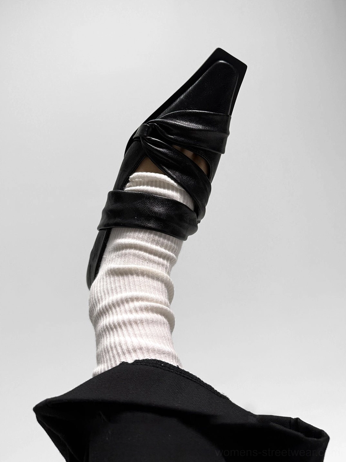 Close-up of a black knotted square-toe leather flat showing the wrapped vamp detail, matte finish, and sculptural toe shape