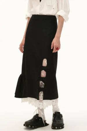 Black lace bow side-slit ruffle hem midi skirt styled with a white blouse, lace socks, and black platform loafers in a front side view