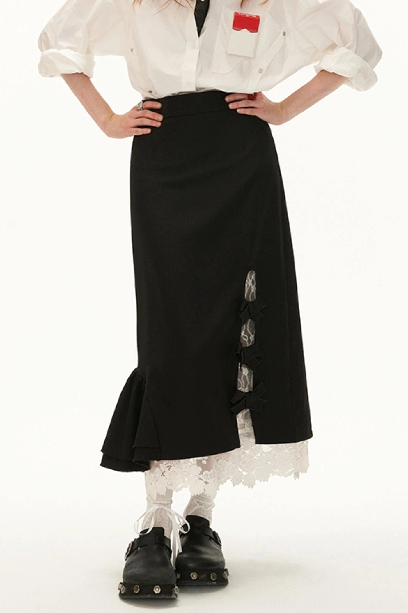 Back view of black lace bow side-slit midi skirt showing the ruffled hem, contrasting lace underlayer, and streetwear outfit styling