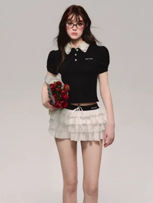 Black cropped polo top with contrast white lace Peter Pan collar and puff sleeves styled with a white ruffle mini skirt