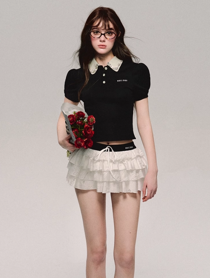 Black cropped polo top with contrast white lace Peter Pan collar and puff sleeves styled with a white ruffle mini skirt