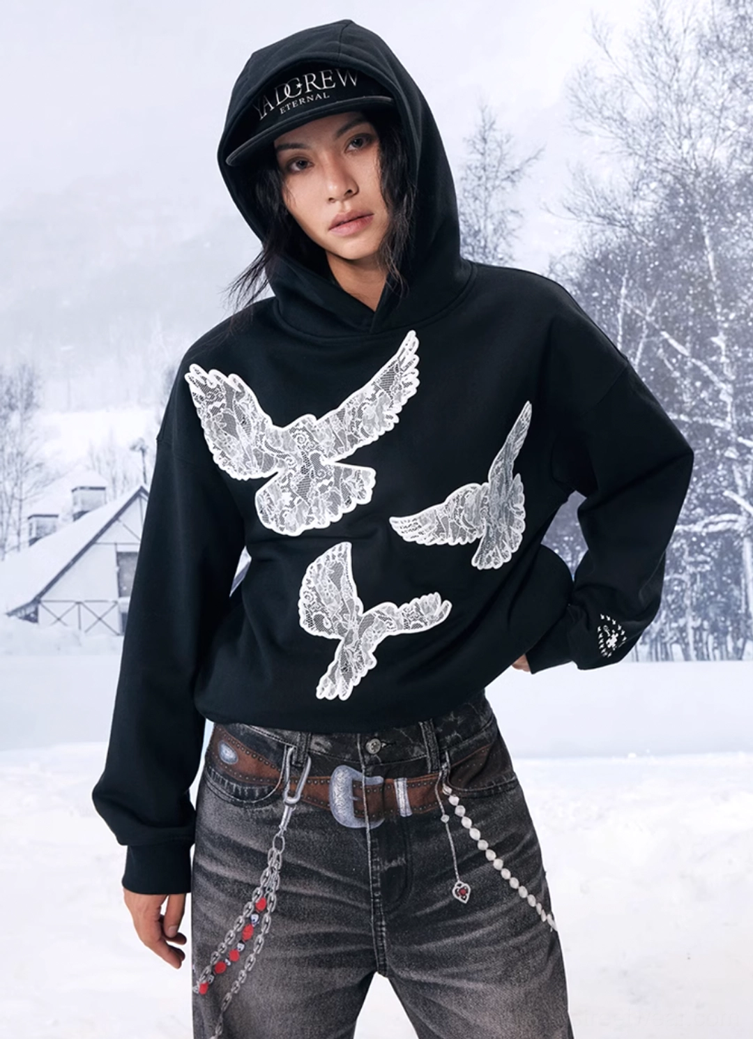Side front view of a black lace dove hoodie styled with vintage denim, a chain belt and casual Korean-inspired streetwear accessories