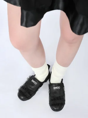 Black lace sport sandals worn with cream socks and a satin mini skirt, showing the Y2K streetwear styling and decorative vamp details
