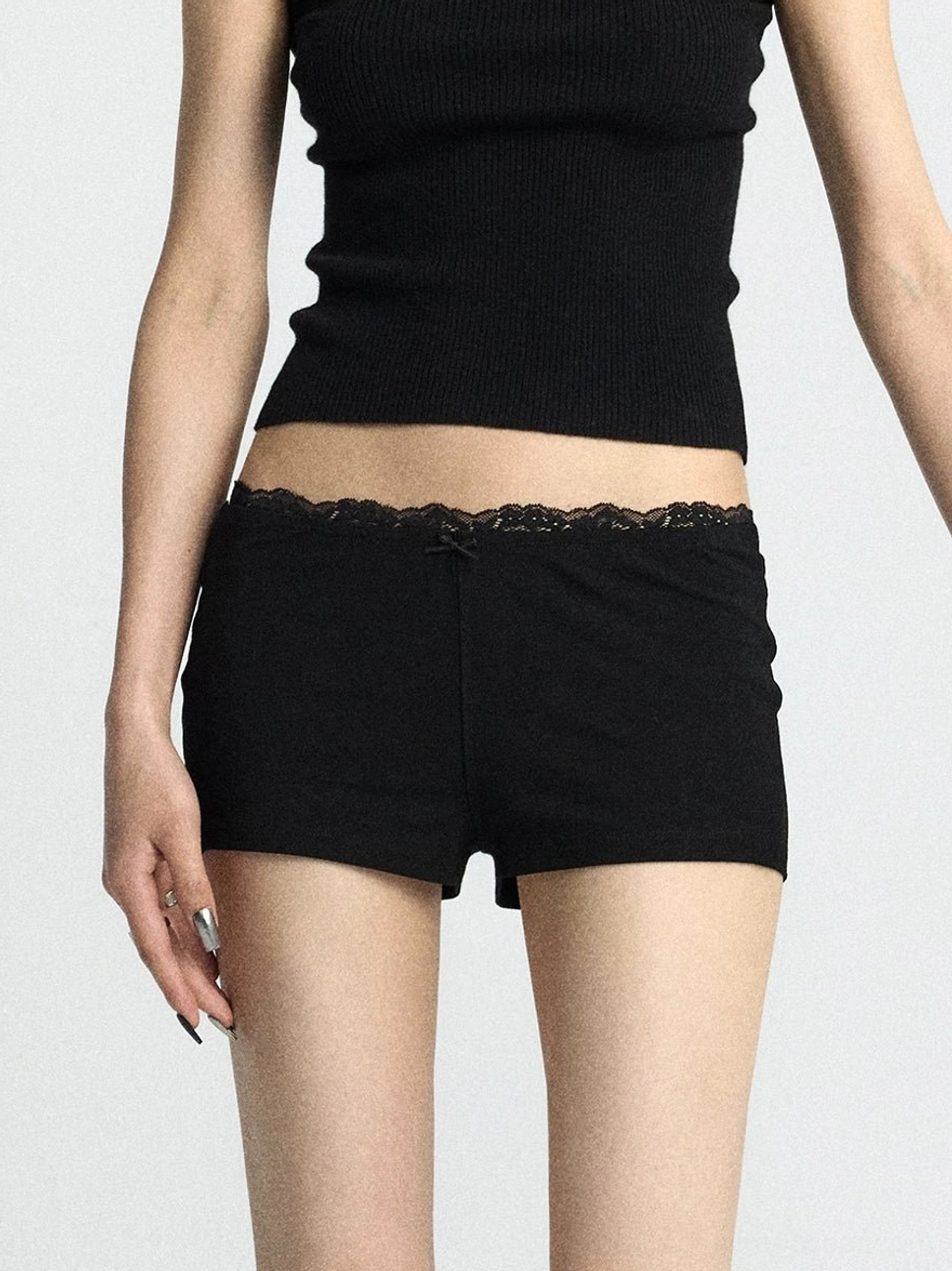 Black lace trim micro shorts with scalloped waistband and small front bow shown in a close up view