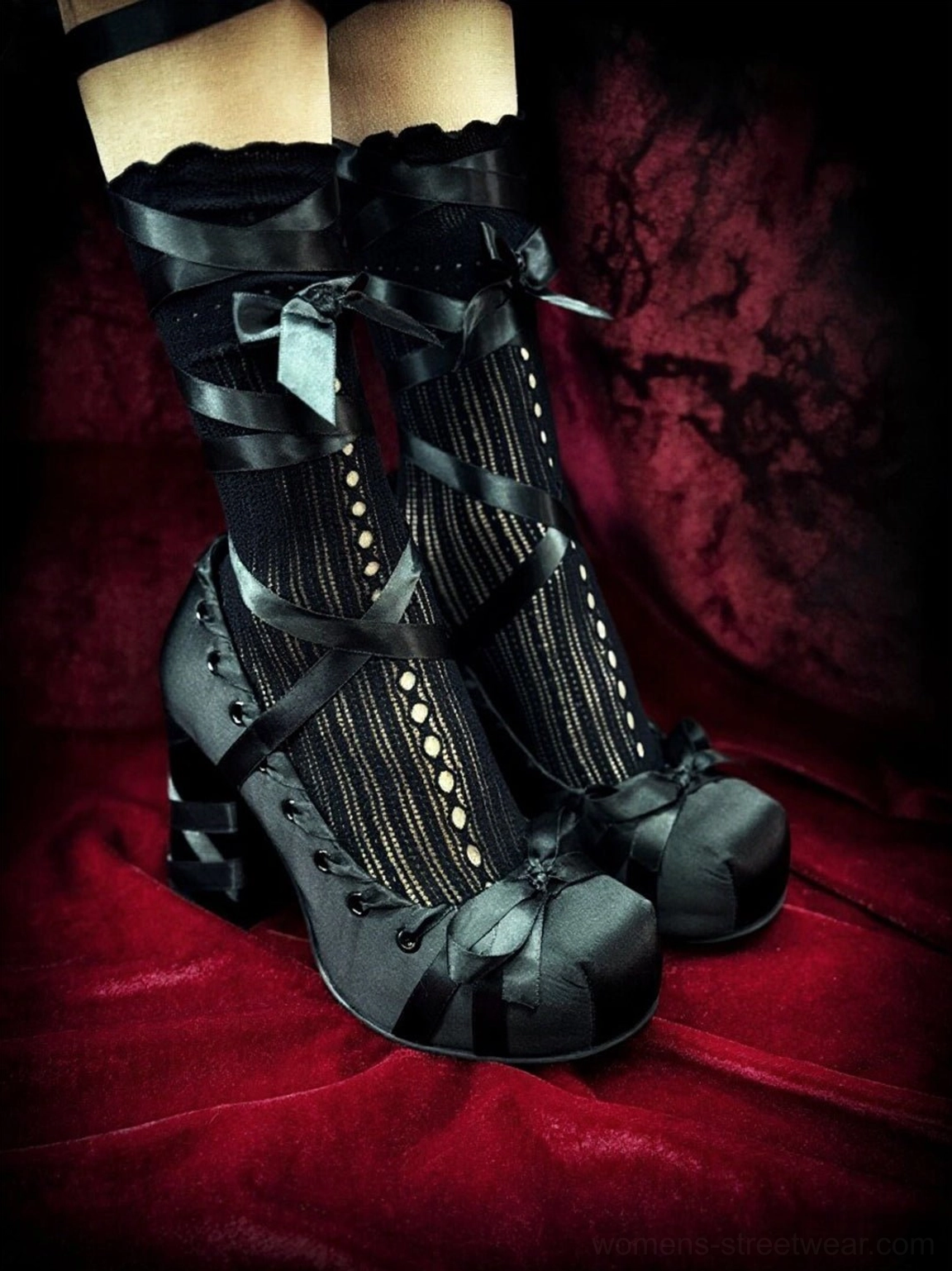 Close-up of black lace-trimmed satin platform pumps with cross straps, studded vamp trim, lace socks, and chunky block heels