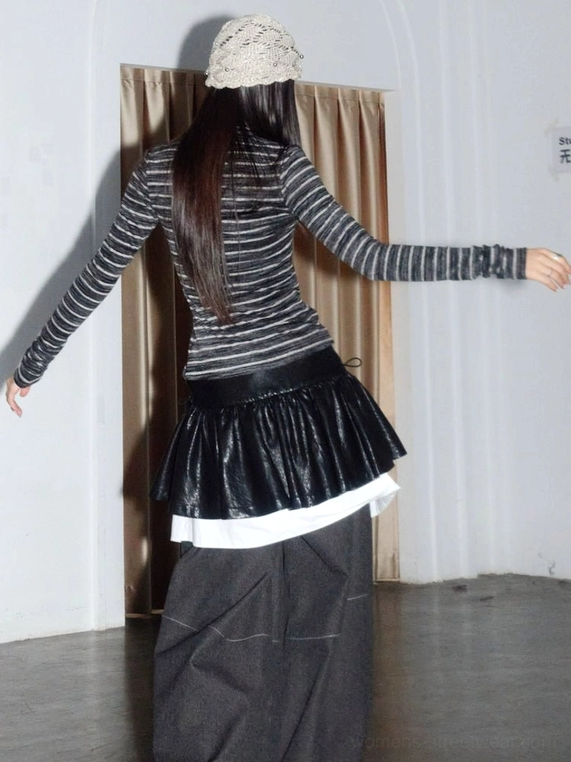 Back view of Asian fashion model styling a black layered faux leather ruffle mini skirt with striped knit top and bucket hat