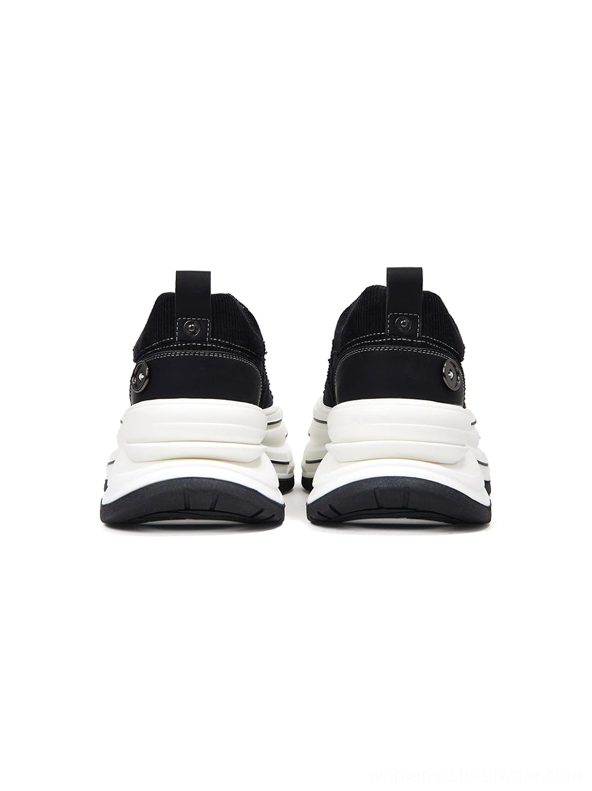Rear view of black layered platform canvas sneakers showing thick white sole, heel pull tabs, and decorative heel badges