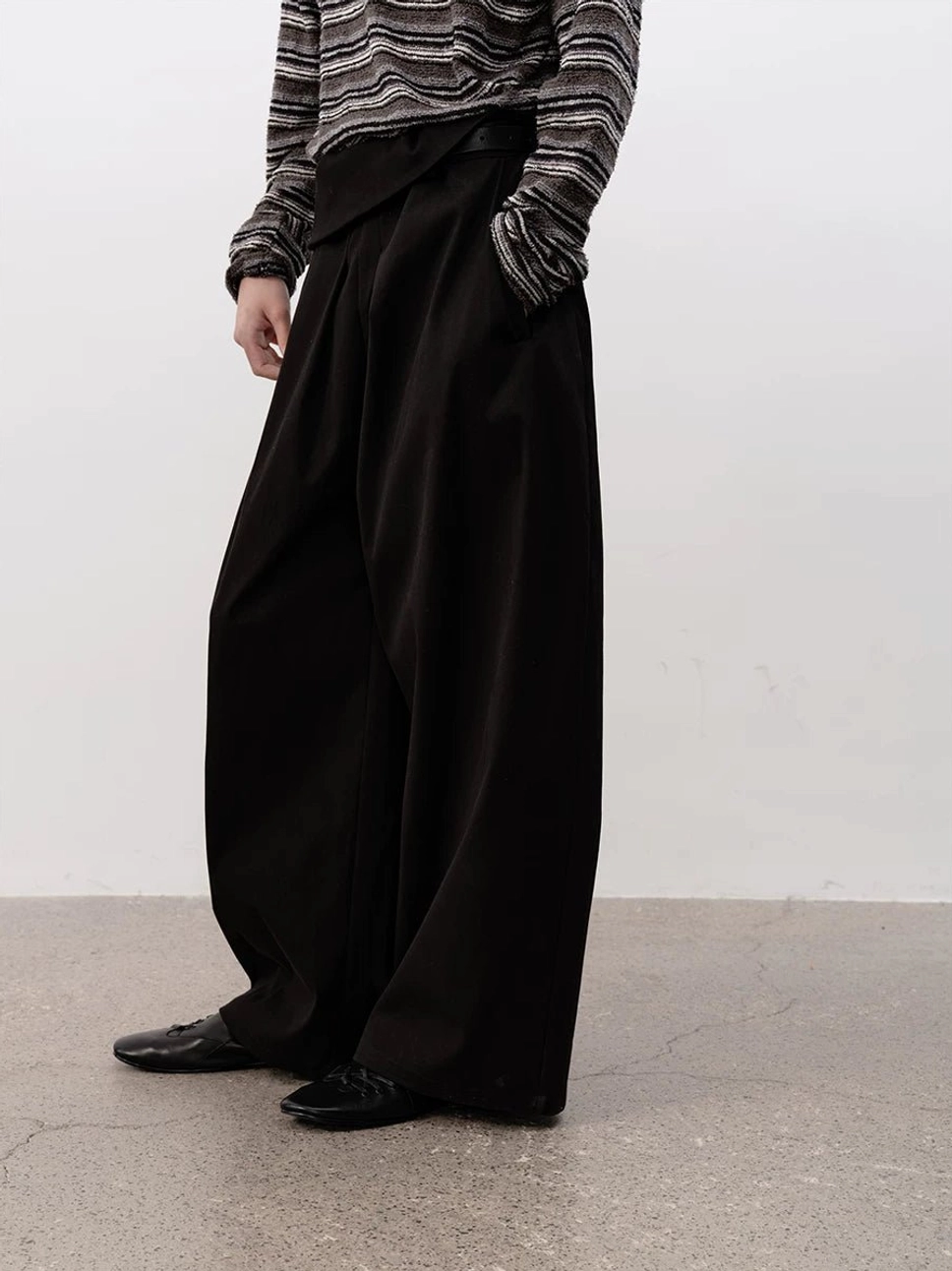 Full-body side styling of black leather ballet sneakers with cropped striped top and high-waisted wide-leg black trousers