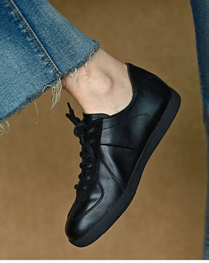 Black leather casual sneakers shown on foot with a sleek stitched upper and minimalist low-top streetwear silhouette