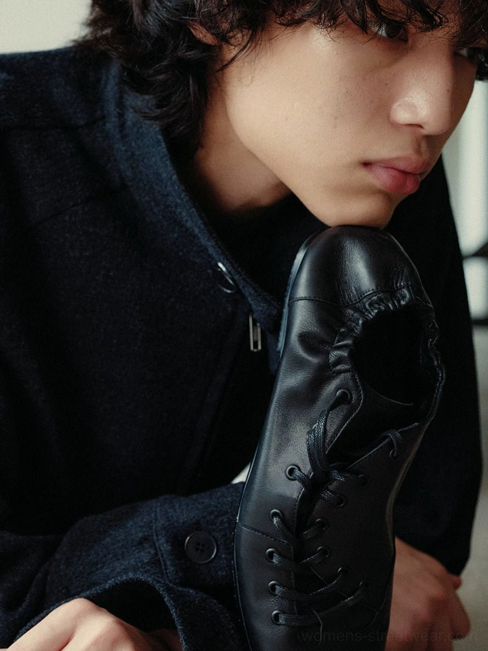Close-up side view of black leather lace-up ballet sneakers with matte finish, asymmetric waxed laces, rounded toe, and low-profile streetwear silhouette