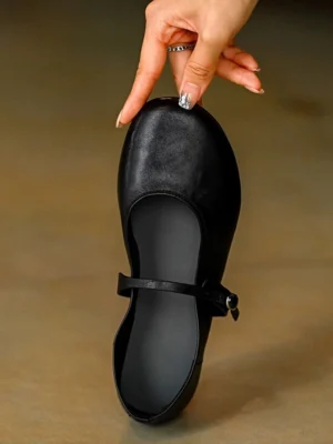 Single black leather Mary Jane flat shoe with rounded toe adjustable ankle strap and silver buckle shown from a top front view