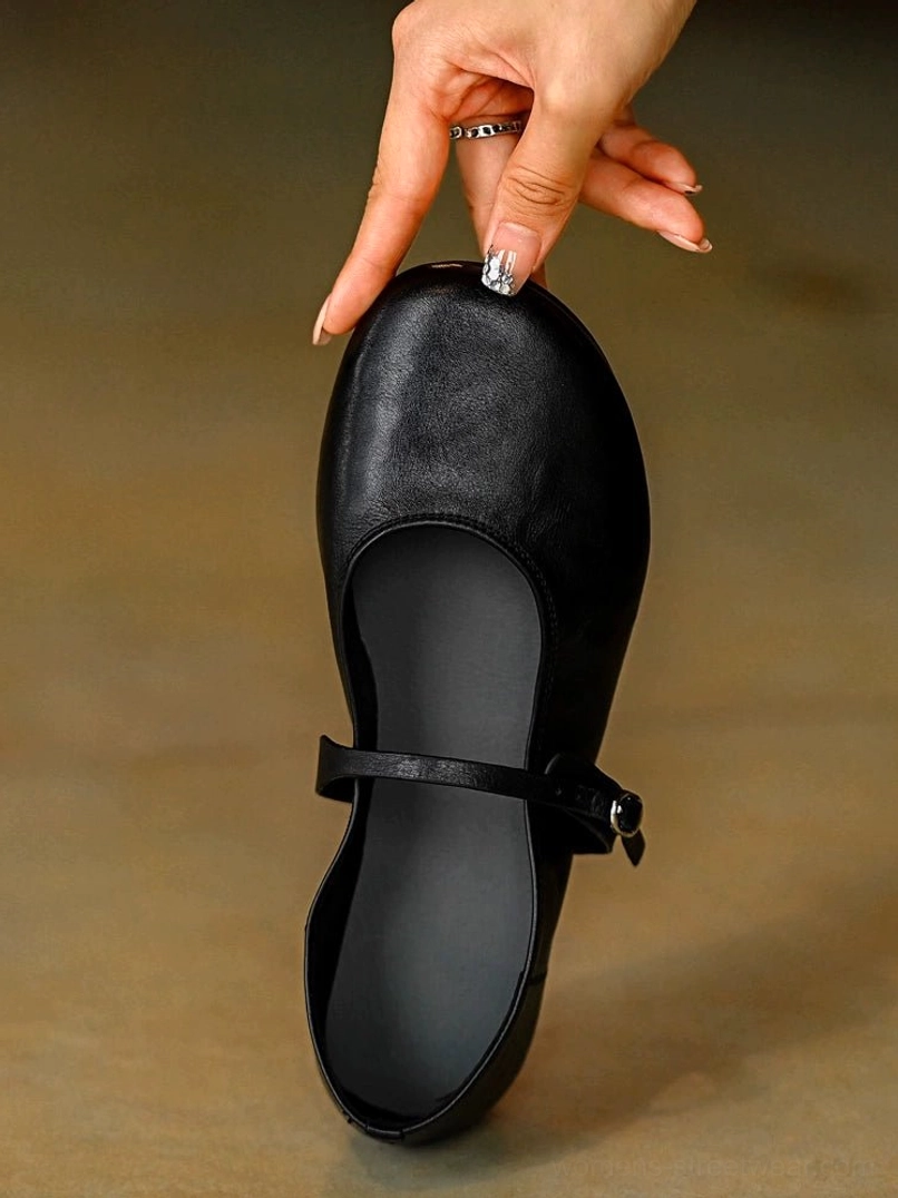 Single black leather Mary Jane flat shoe with rounded toe adjustable ankle strap and silver buckle shown from a top front view