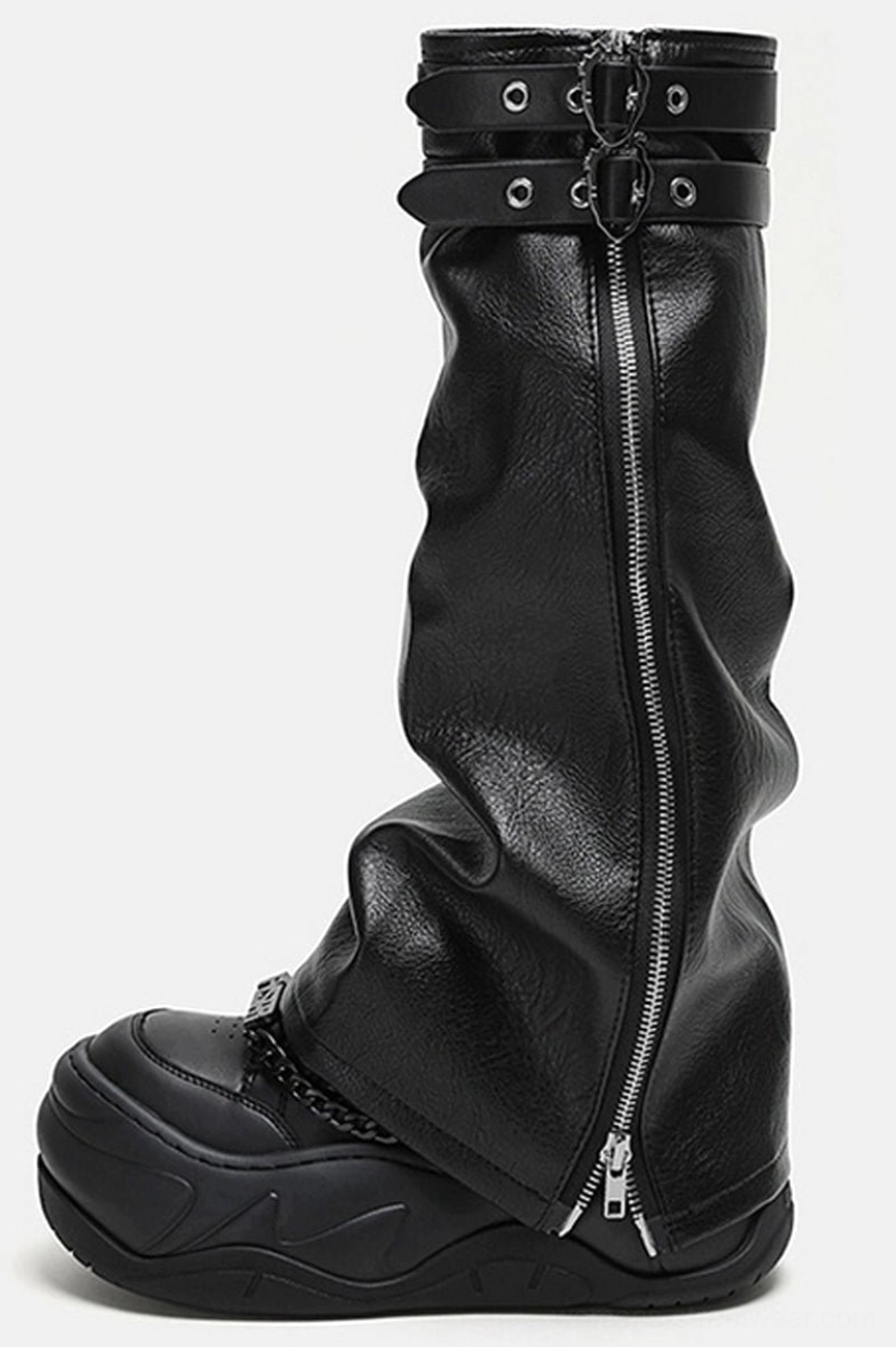 Side view of black leather platform footwear with chain-decorated sneaker toe, buckle straps, and center zipper detail