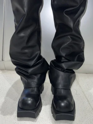 Black leather platform derby shoes styled with black leather trousers, showing the thick block platform sole in a modern streetwear outfit
