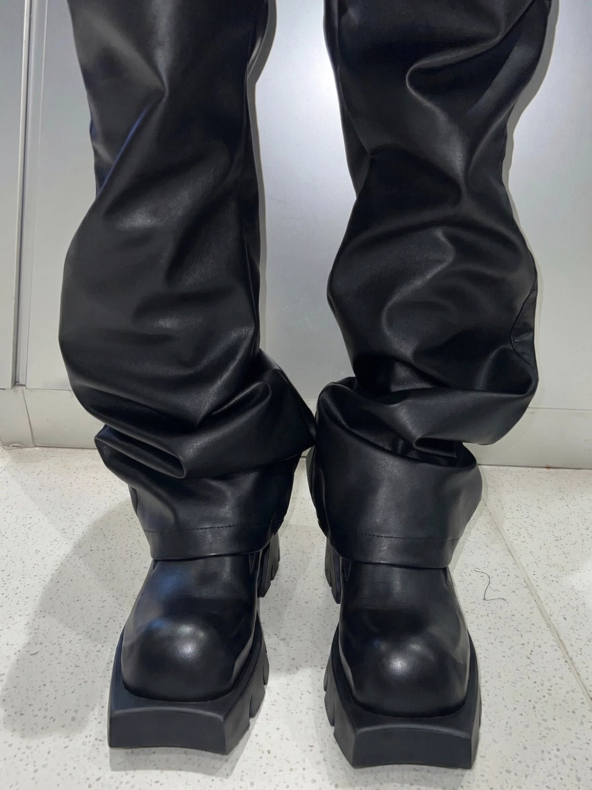 Black leather platform derby shoes styled with black leather trousers, showing the thick block platform sole in a modern streetwear outfit