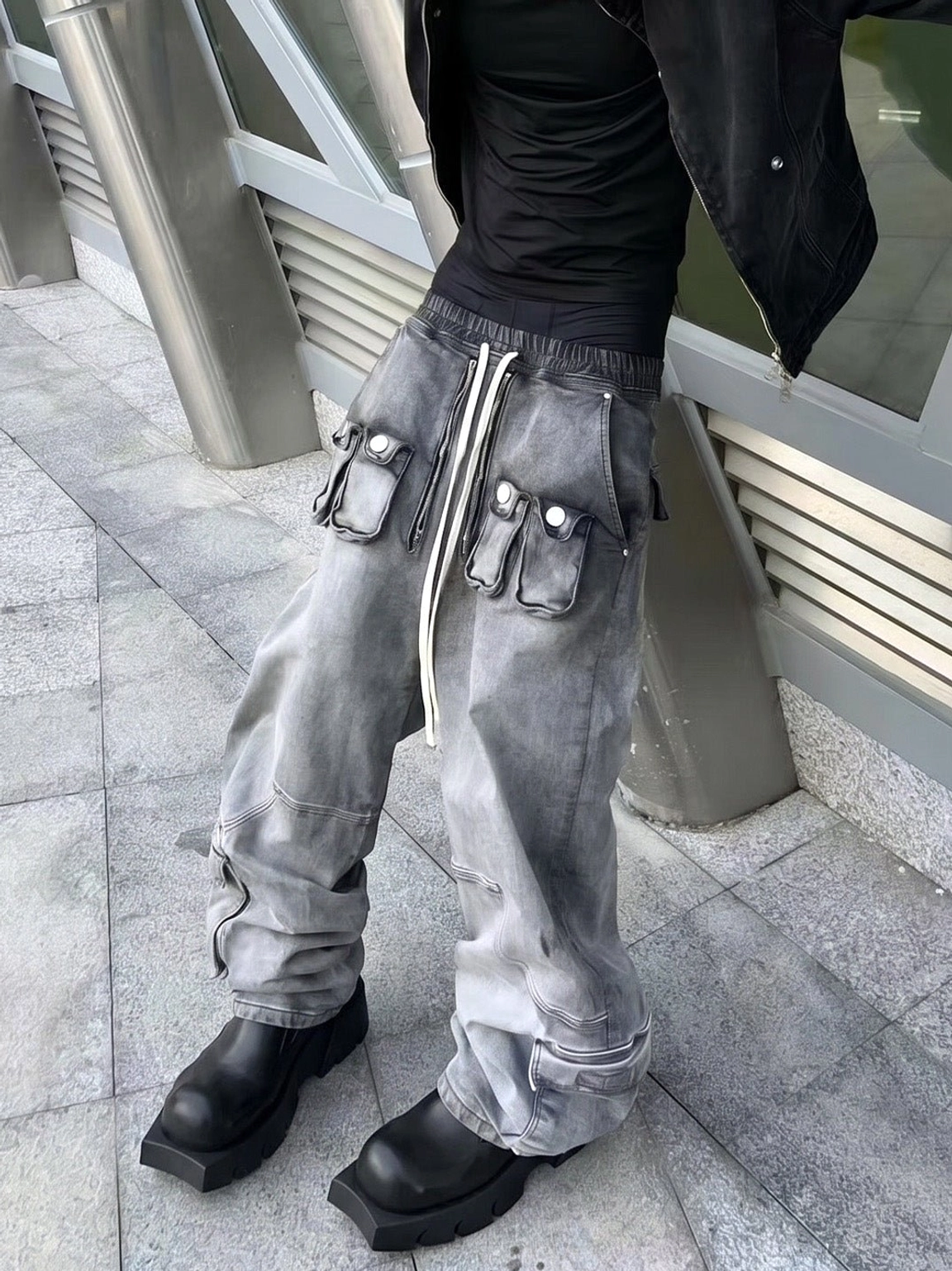 Black leather platform derby shoes styled with gray cargo jeans for a casual urban streetwear look on a modern sidewalk