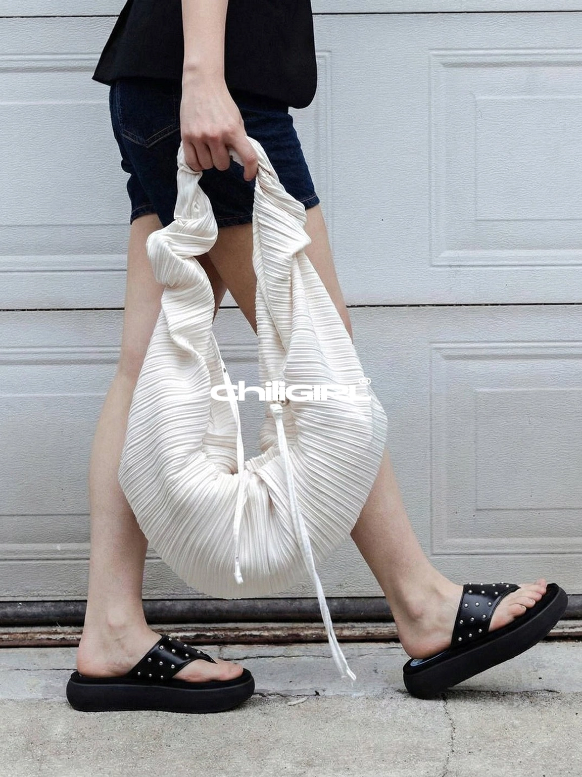 Black leather rivet platform sandals worn with denim shorts and a white pleated tote