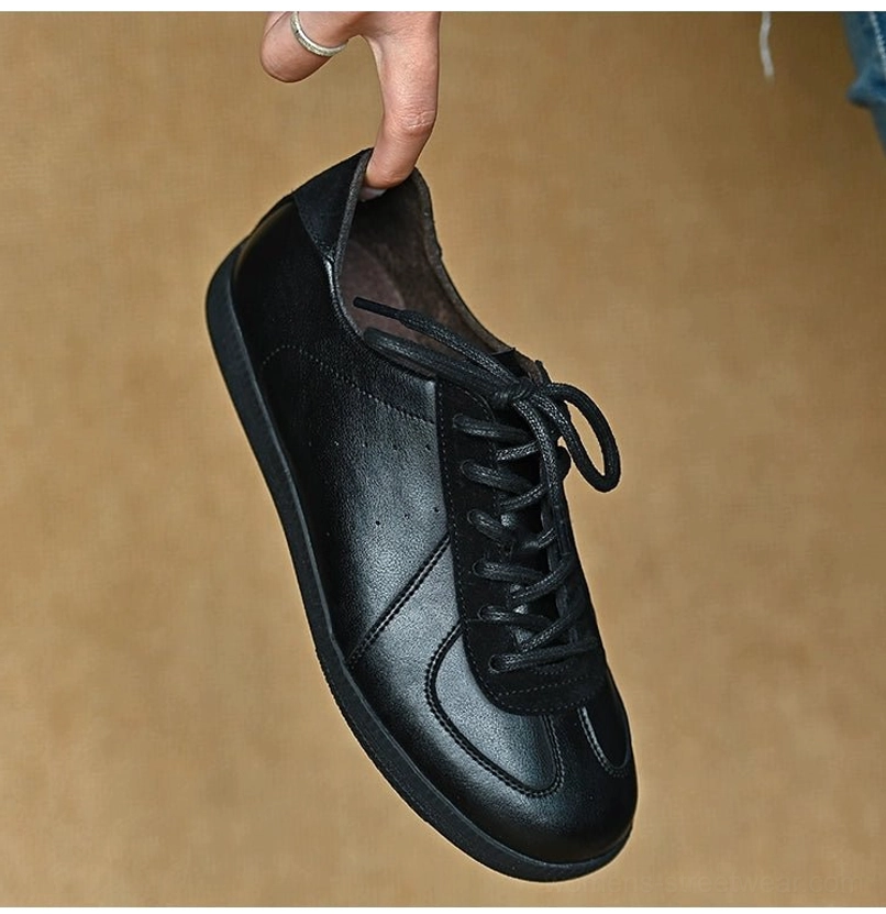 Front side view of a black leather retro sneaker with perforated toe box, polished upper, and low-profile rubber sole