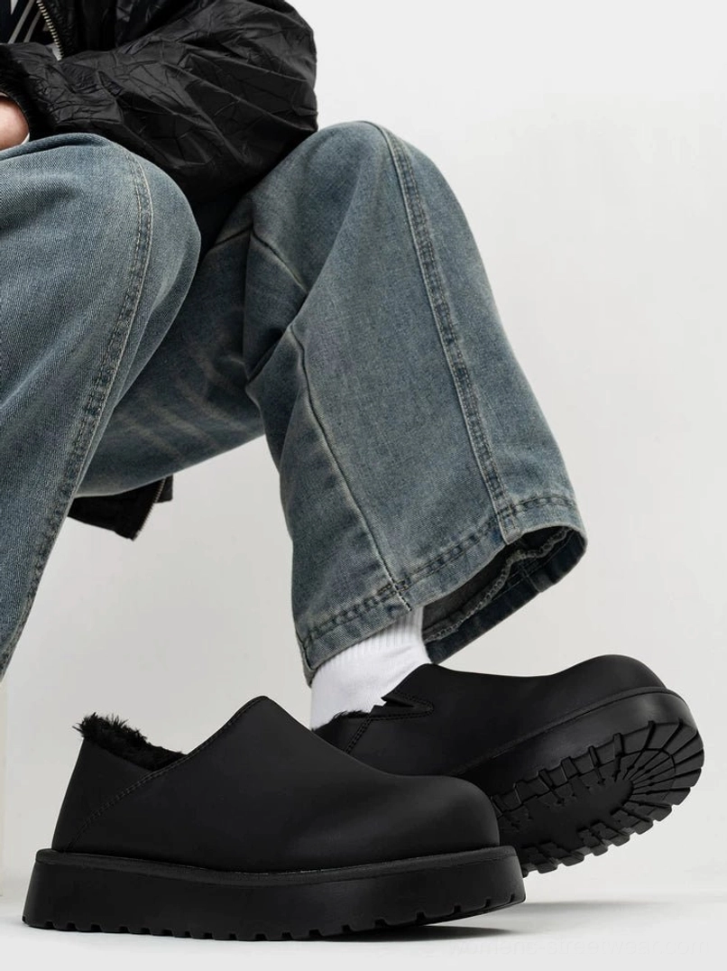Black leather and tan suede shearling-lined platform slip-on clogs displayed on a seated model, showcasing two versatile streetwear colorways