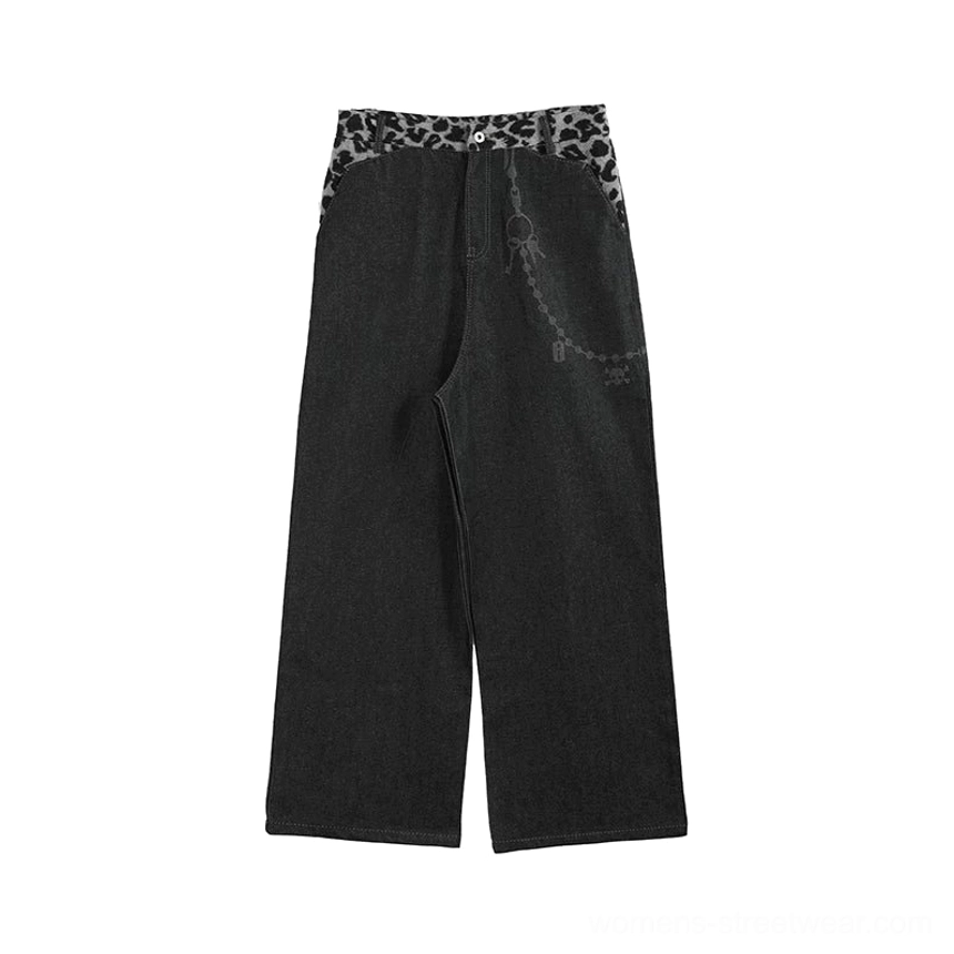 Flat lay front view of black denim leopard waistband chain baggy jeans showing the button closure, pocket construction, and graphic details