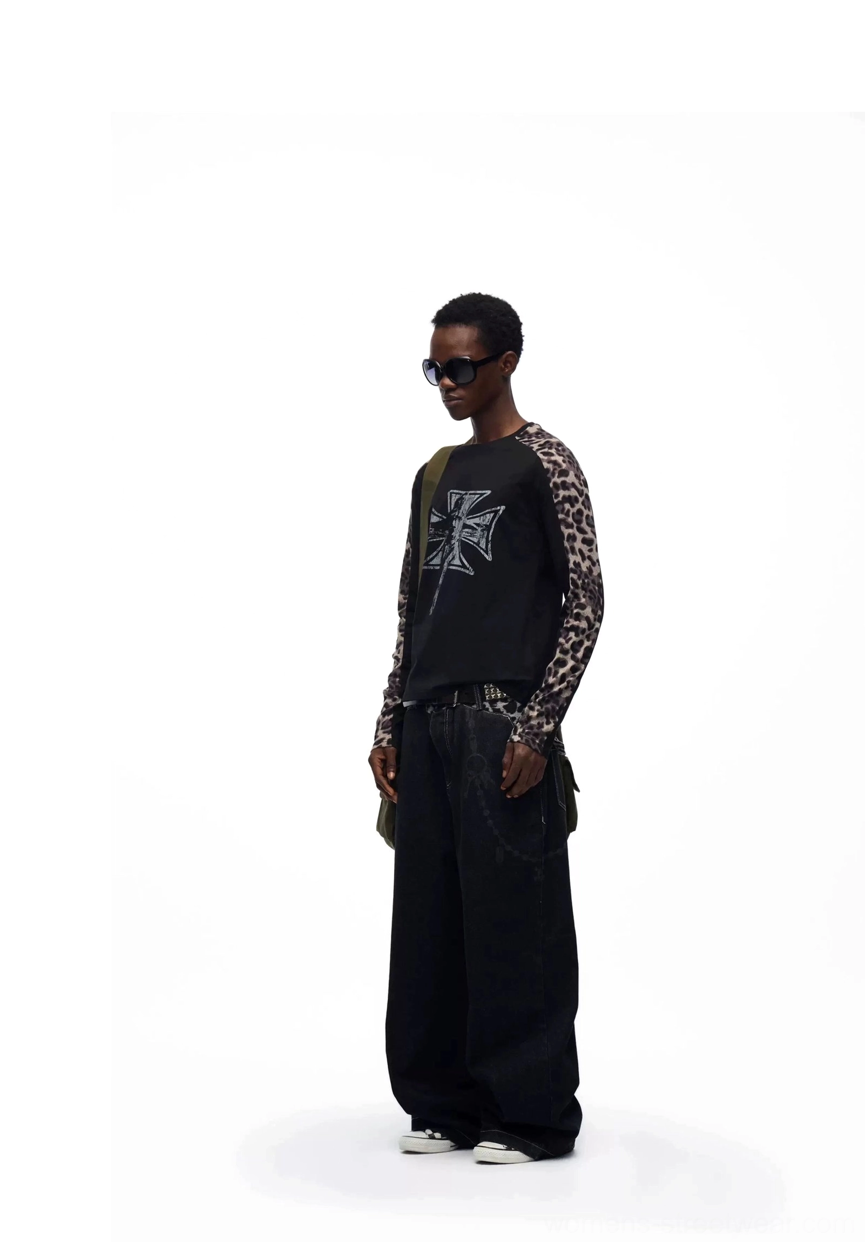 Front side studio view of black leopard waistband chain baggy jeans worn with a cross print top and alternative streetwear styling