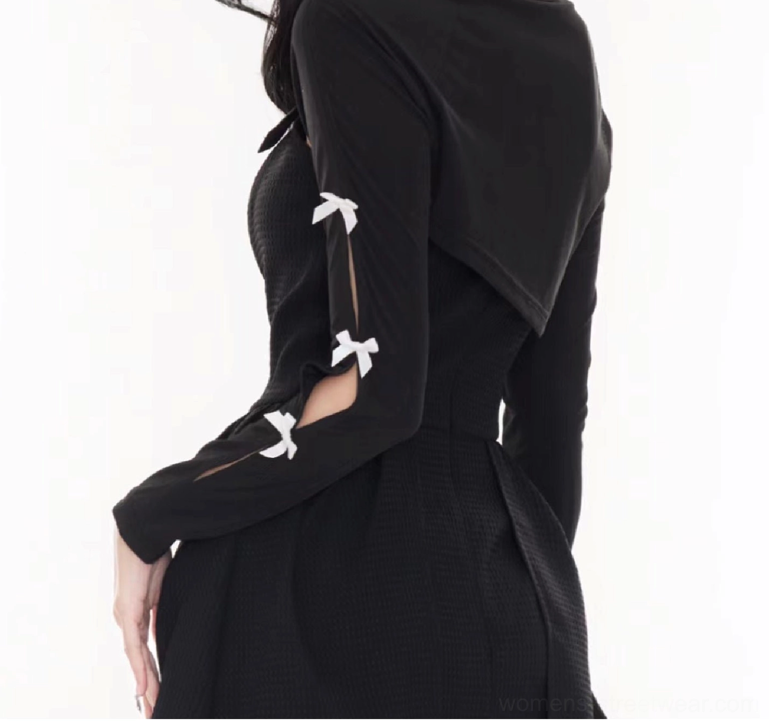 Back three-quarter product view of a black lightweight cropped bolero cardigan with slit sleeves and bow decorations