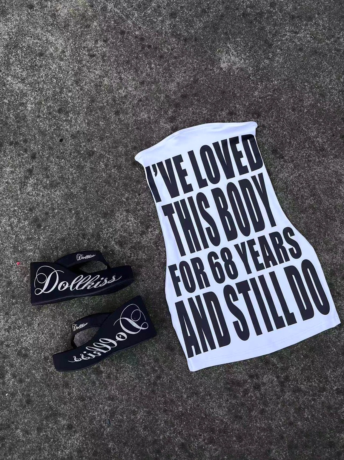 Black logo print platform wedge flip-flop design displayed in a miniature flat lay with graphic tank top