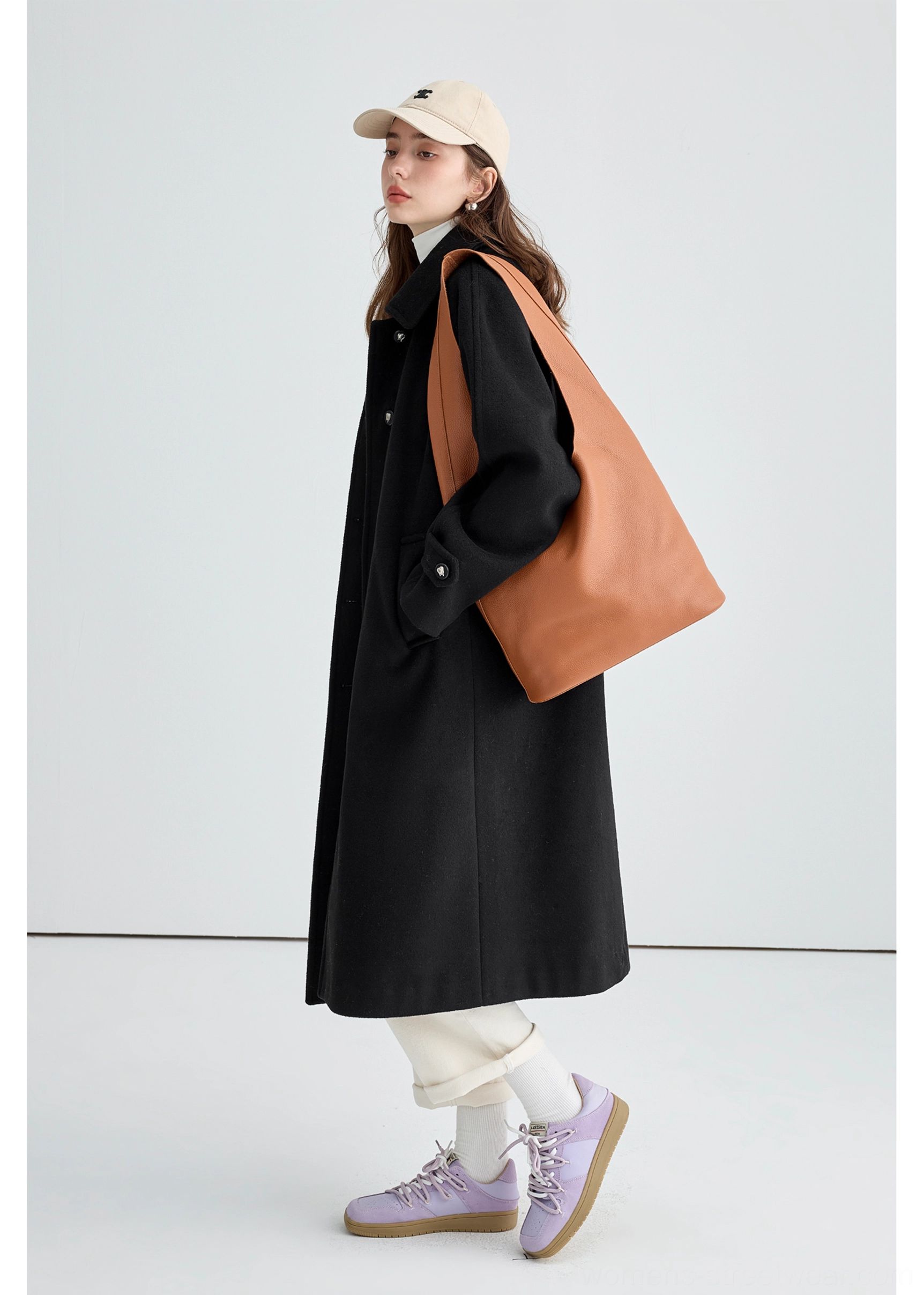 Back side view of black long insulated streetwear overcoat showing relaxed long silhouette and neat tailored collar