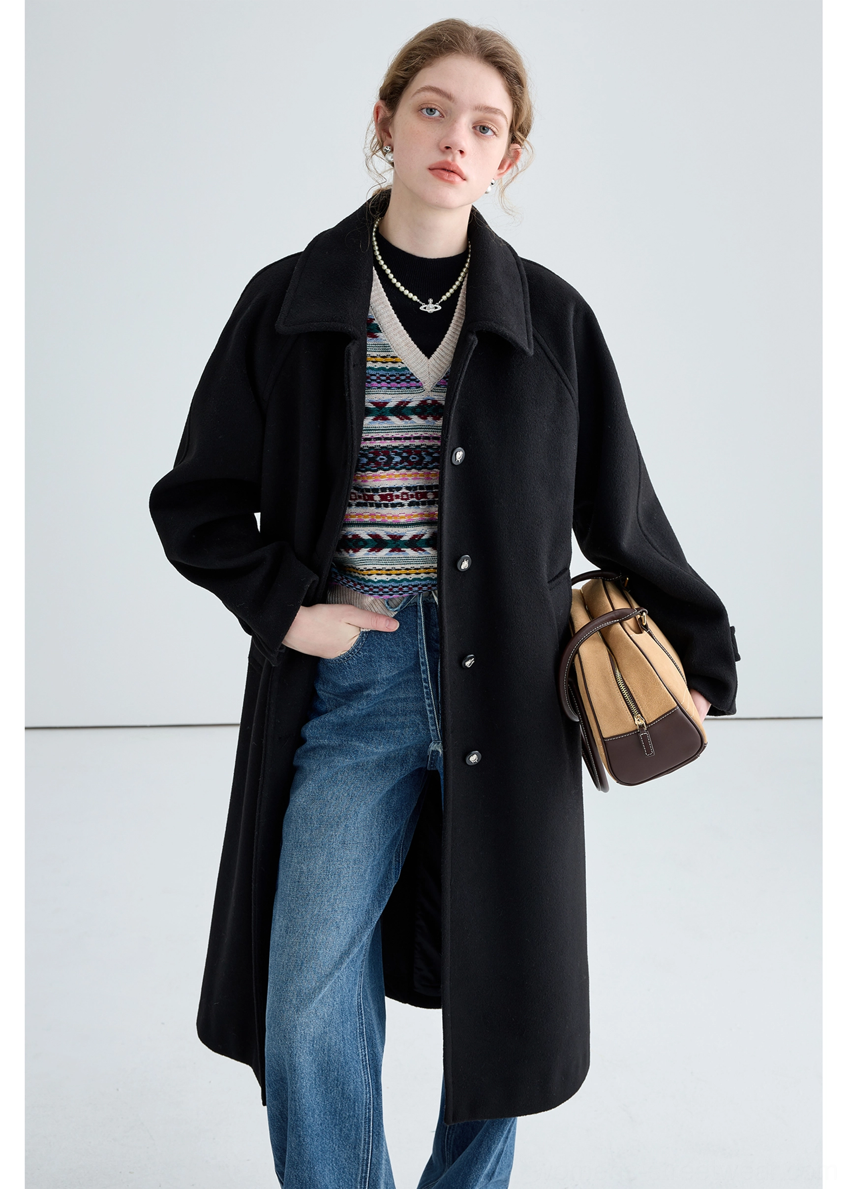 Black long insulated streetwear overcoat styled with denim layered knitwear and metal button fastenings