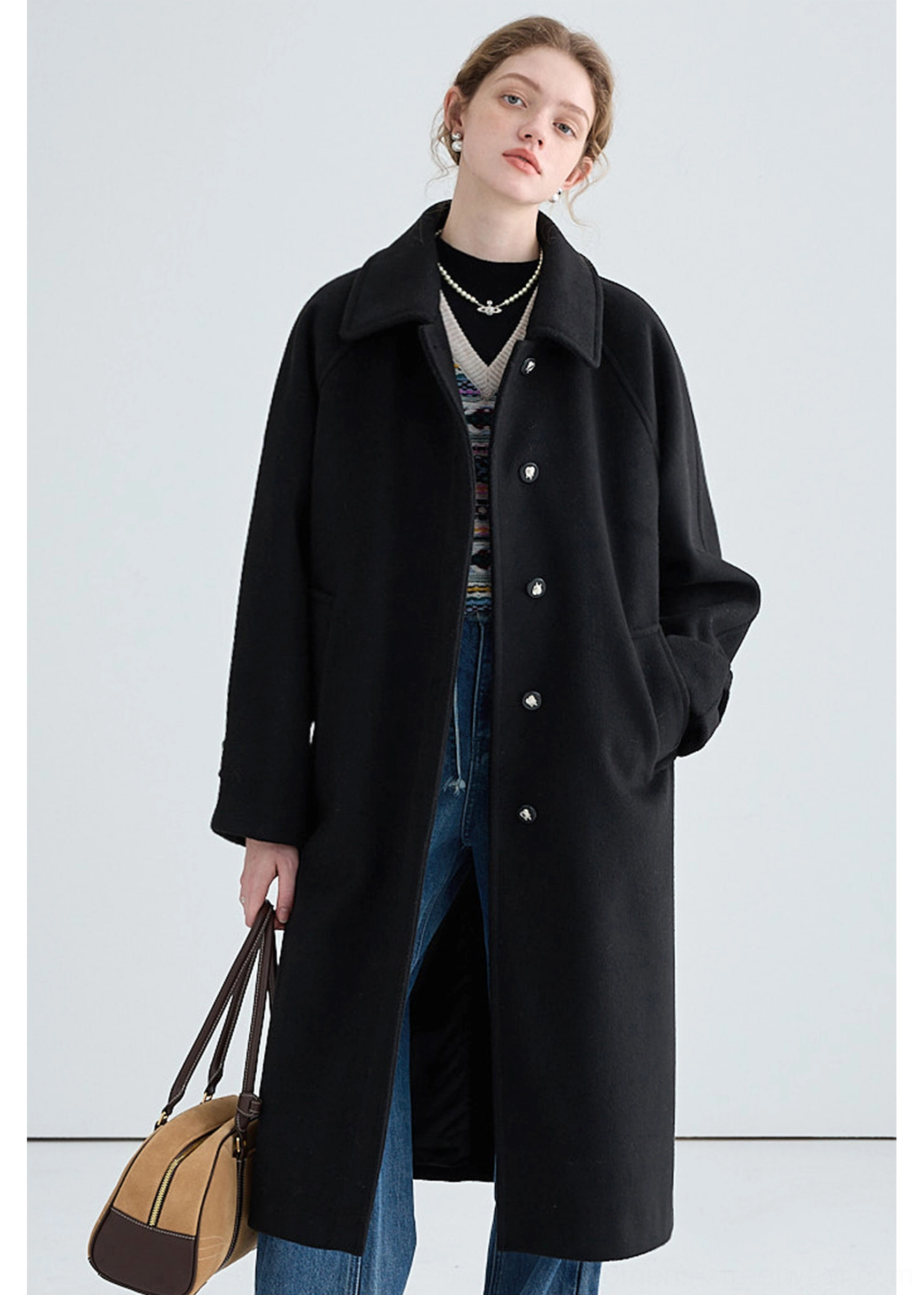 Black long insulated streetwear overcoat front full-body outfit with metal buttons side pockets and relaxed silhouette