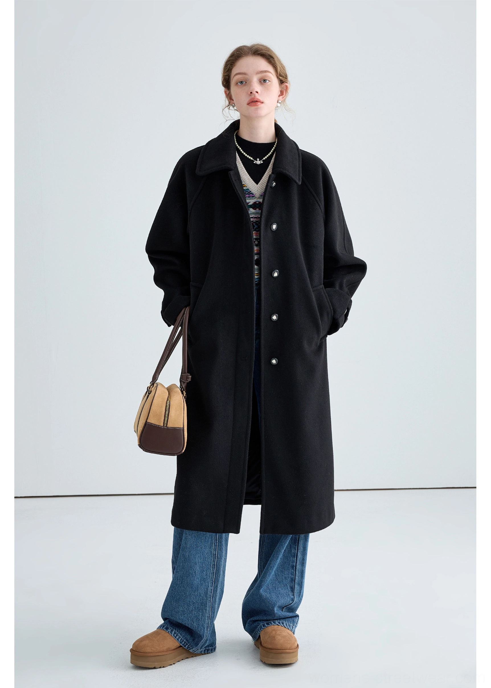 Black long insulated streetwear overcoat product image showing minimalist tailored cold-weather styling